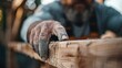©  Shomixer - A carpenter's hand, weathered from experience, is meticulously working on a wooden project, representing craftsmanship, dedication, and the art of woodworking in a rustic setting.
