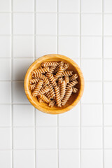 Wall Mural - Uncooked whole grain pasta. Raw fusilli in bowl. Top view.