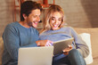 © Prostock-studio - Smiling Man And Woman Using Laptop And Digital Tablet Websurfing And Chatting In Social Media Sitting On Sofa Indoor