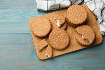 Wall Mural - Tasty sandwich cookies on light blue wooden table, above view. Space for text