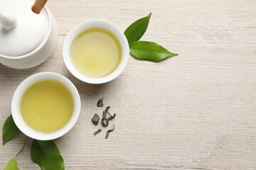 Canvas Print - Refreshing green tea in cups, sugar bowl and leaves on wooden table, flat lay. Space for text