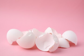 Wall Mural - Pile of broken eggshells on pink background, closeup