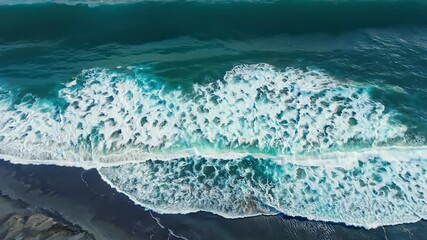 Wall Mural - Waves crash on a black sand beach, viewed from above. The water is clear and turquoise, and the foam is white