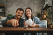© Miljan Živković - Adult couple save money coins in the piggy bank at home