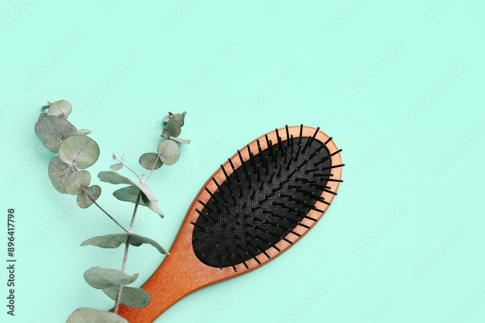 Hair brush with eucalyptus branch on mint background