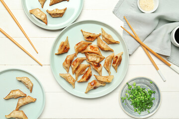 Wall Mural - Plates with tasty Chinese jiaozi, onion and sauce on white wooden background