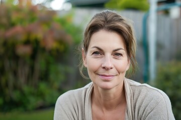 Wall Mural - Smiling mature attractive housewife posing at her home backyard looking at the camera