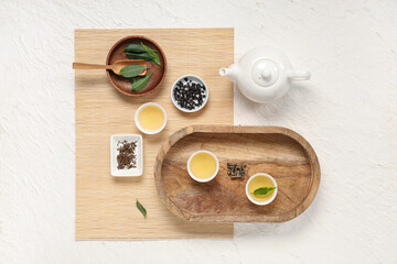 Poster - Teapot with cups, bowls of dry tea and leaves on white background