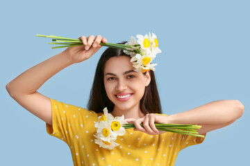 Sticker - Beautiful young woman with daffodil flowers on blue background