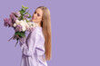 © Pixel-Shot - Beautiful young happy woman with bouquet of lilac flowers on purple background