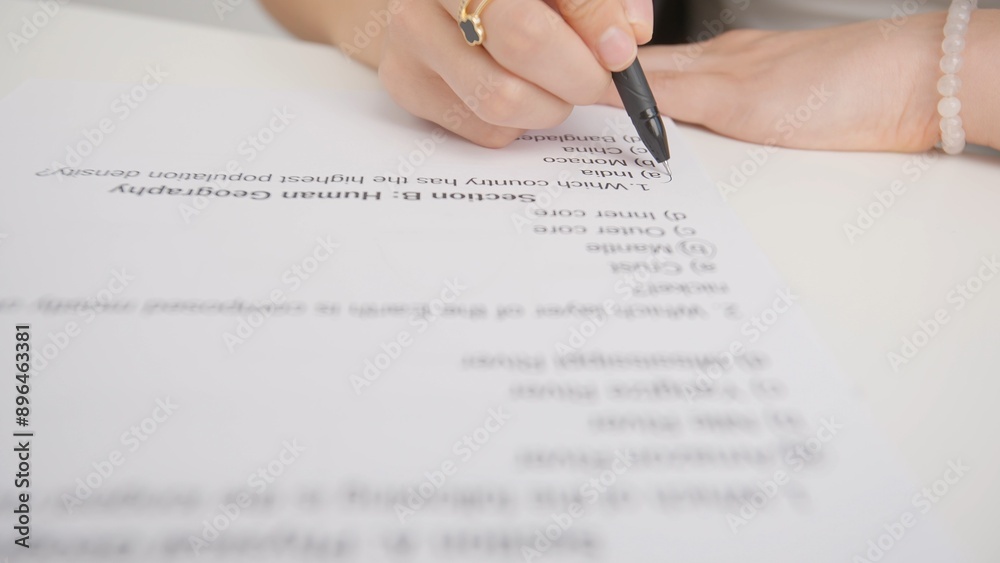 Female circles correct answers in standard exam test paper with black ...
