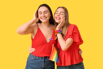 Poster - Beautiful young lesbian couple with LGBT flag on yellow background