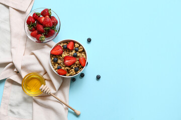 Wall Mural - Napkin, bowls with tasty granola and berries on blue background