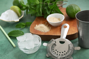 Wall Mural - Wooden cutting board, strainer and ingredients for mojito on green background, closeup