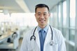 © Baba Images - Smiling portrait of a middle aged Asian male doctor in hospital