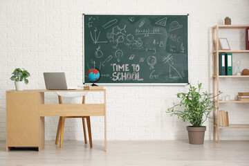 Poster - Teachers desk with laptop and blackboard in light classroom