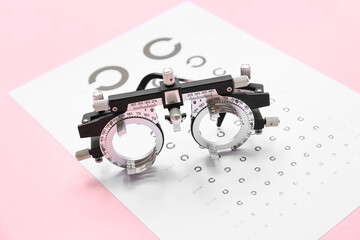 Wall Mural - Optical trial frame with eye test chart on pink background