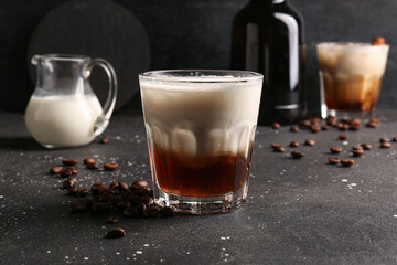 Wall Mural - Glass of White Russian cocktail with coffee beans and jug of cream on black background