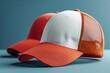 © Ghiska - Two red and white trucker caps mockup, one cap is blank the other has orange mesh on it.