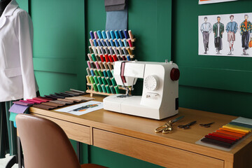 Poster - Tailor's workplace with sewing machine, thread spools and fabric samples in atelier