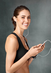 Poster - Portrait, online and woman with earphones for fitness, studio and streaming with app in cellphone and smile. Grey background, music and sportswear for exercise, sound and person in morning and gym