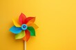 © panumas - Close-up of a colorful pinwheel on a yellow background.
