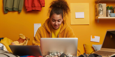 Poster - Young professional is working from her home office, surrounded by clothes and personal belongings