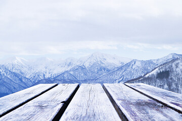 Landscape empty brown wooden planks or table with winter alpine high mountains were covered with white snow trees were dry and leafless. Ideal for product placement. Sky was covered with white mist.