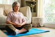 © CandyRetriever  - Happy Asian senior mature woman meditating in lotus pose in living room. Wellbeing elderly grandmother enjoy healthy lifestyle relaxing with meditation deep breath and practicing yoga exercise at home