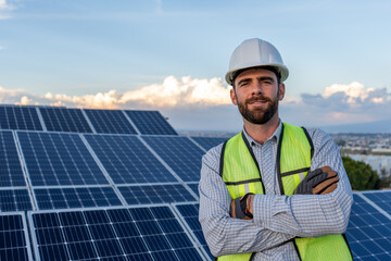 portrait of an engineer smiling with confidence in front of a solar panel power station, handsome male technician electrician looking at camera, photography with copy space for text