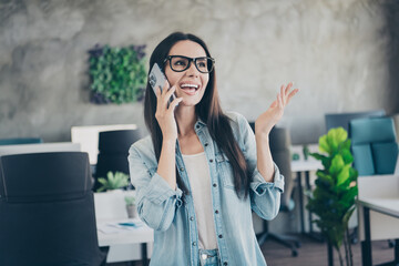 Poster - Photo of excited charming lady secretary wear denim jacket smiling talking modern device indoors workshop workstation loft