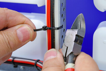 Sticker - The hand installs a plastic screed on insulated wires. Close-up. Soft focus.