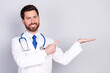 © deagreez - Photo of professional qualified doctor point finger hold empty space wear white coat isolated on grey color background