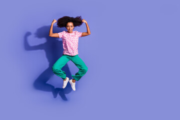 Wall Mural - Full length photo of lovely young lady jump flexing muscles dressed stylish pink garment isolated on violet color background