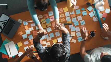 Poster - Top view of business team giving high five to celebrate project while standing at table with sticky notes and laptop. Aerial view of designer clapping hands to congratulate successful idea. Symposium.