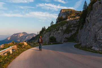 Man with backpack walking on road curve in Loser panoramastrasse area at sunrise