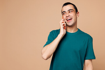 Sticker - Young middle eastern man wears blue t-shirt casual clothes talk speak on mobile cell phone conducting pleasant conversation isolated on plain pastel light beige background studio. Lifestyle concept.