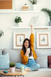 © nenetus - Excited young woman celebrating something while using smartphone relaxing in couch at home