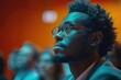 © Katavudh - A young man with glasses looks intently at a speaker during a presentation or lecture.  The image is full of blue and orange tones, creating a vibrant and captivating scene.