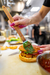 Wall Mural - Close-up of hands applying glaze to a gourmet burger with a brush