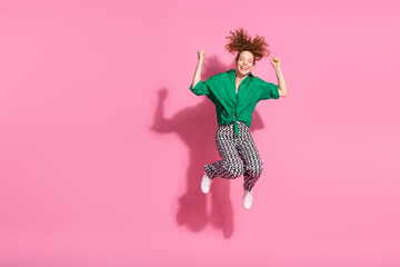 Sticker - Photo of lucky attractive lady dressed green shirt jumping high rising fists empty space isolated pink color background