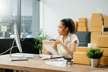 Young business owner woman prepare parcel box and standing check online orders for deliver