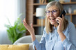 © Liubomir - Senior woman with glasses talking on phone indoors looking upset or frustrated. Elderly lady having difficult conversation expressing emotions.