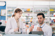 © winnievinzence - Two pharmacists counting drug pills arranging assortment working in drug shelves counter
