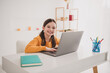 © deagreez - Portrait of smart schoolkid beaming smile study laptop desk white interior apartment indoors