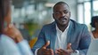 © WS Studio 1985 - Engaged in the Exchange: A young Black professional articulates his point during a lively business meeting, his passion evident in his focused expression.
