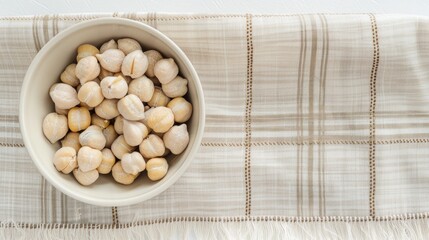 Wall Mural - A bowl of cooked chickpeas sits on a white table with parsley sprigs and scattered chickpeas