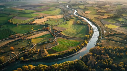 Wall Mural - Showcase an aerial view of a river winding through a rural landscape, highlighting the patchwork of fields and forests