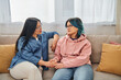 © LIGHTFIELD STUDIOS - An Asian mother and her teenage daughter in casual wear engage in a deep conversation while sitting on a cozy couch.