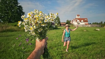 Canvas Print - woman running across the field for a bouquet of daisies, field bouquet, happy girl, blue sky, clouds, old houses, woman in sherts, summer